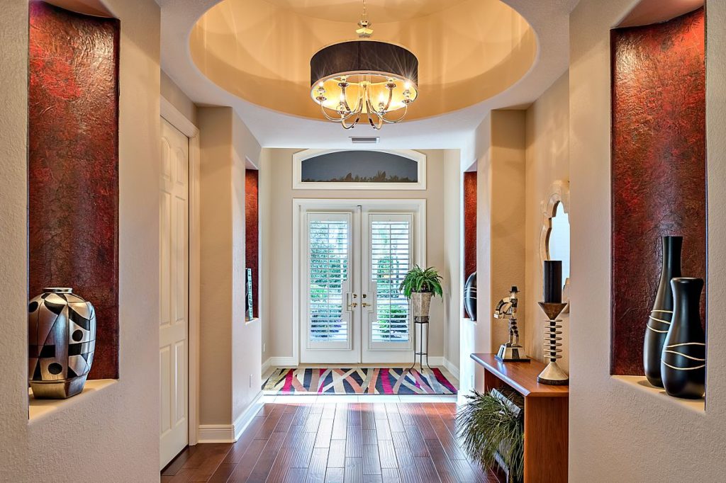 A long dark entryway was lightened with wallpaper, paint, lighting and flooring.