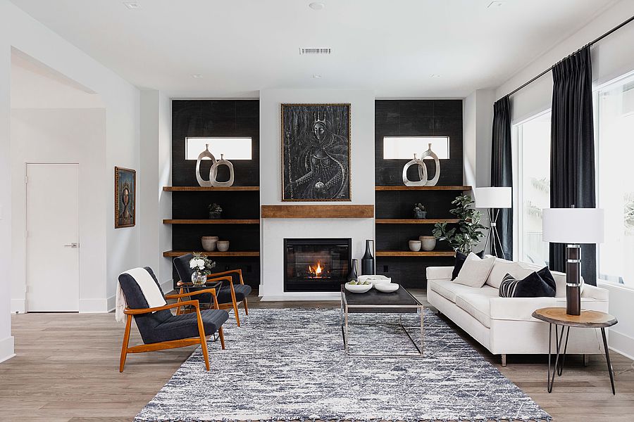 Stark white walls contrast with an array of black decoration pieces such as the charcoal sofa, black and white geometric draperies and art.